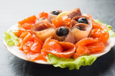 Bir tabak füme tuz, çiğ beyaz balık fileto ve somon sunan gurme restoranı. Yayın balığı, somon eti plaka yakın çekim üzerinde zeytinli ile incelik taze deniz ürünleri yemek.