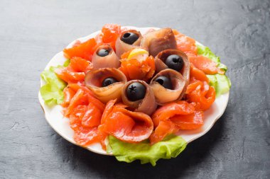 Bir tabak füme tuz, çiğ beyaz balık fileto ve somon sunan gurme restoranı. Yayın balığı, somon eti plaka yakın çekim üzerinde zeytinli ile incelik taze deniz ürünleri yemek.