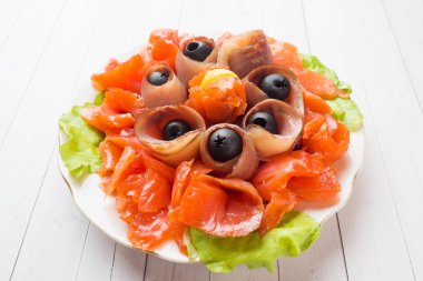 Bir tabak füme tuz, çiğ beyaz balık fileto ve somon sunan gurme restoranı. Yayın balığı, somon eti plaka yakın çekim üzerinde zeytinli ile incelik taze deniz ürünleri yemek.