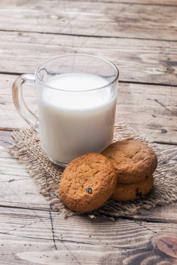 Doğal yulaf ezmeli kurabiye ve bir bardak süt bir ahşap zemin üzerinde. Rustik tarzı kopya alanı