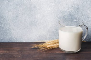 Bir bardak süt ve rustik bir arka plan üzerinde buğday dalı. Ürün için bir yer. Kopya alanı.