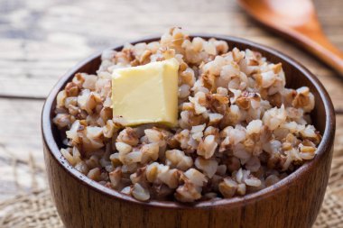 Bir parça tereyağı bir ahşap kase rustik bir tablo ile haşlanmış buğday