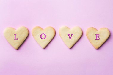 Ev yapımı kurabiye pastel pembe bir arka plan üzerinde bir kalp şeklinde. Uzay kopyalayın. Kavram Sevgililer günü.
