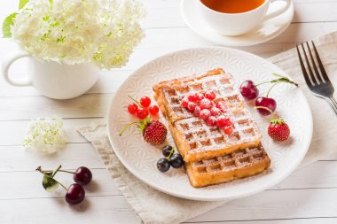Bir plaka üzerinde yaz meyveleri ile ev yapımı gözleme. Bir fincan çay üzerinde masa lambası. Seçici odak.