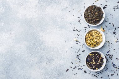 Kuru çay yaprakları ve çiçekleri kase gri arka plan üzerinde çeşitli