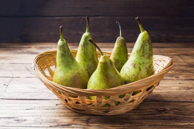 Ahşap rustik arka plan üzerinde bir sepet içinde taze sulu armut konferans