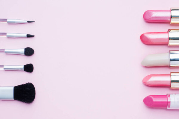 Set of colored pink lipsticks and blush on pink background. Women's cosmetics. Selective focus. Copy space