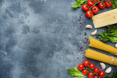 Ham İtalyan makarna spagetti ve malzemeyi kiraz domates peynir yeşillik yemek. İtalyan yemeği koyu taş arka plan. Kopya alanı ile Üstten Görünüm.