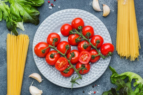 Ham İtalyan makarna spagetti ve malzemeyi kiraz domates yeşillik yemek. İtalyan yemeği koyu taş arka plan. Kopya alanı ile Üstten Görünüm.