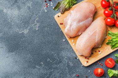 Yeşillik, domates ve baharat kopya alanı ile karanlık bir arka plan üzerinde çiğ tavuk göğsü fileto