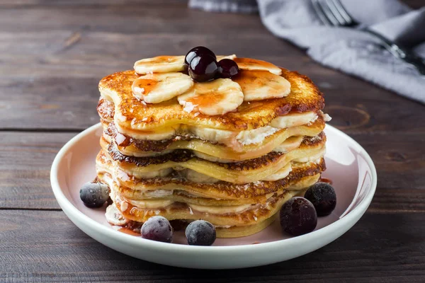 Pastel de tortitas con plátanos y jarabe de bayas, enfoque selectivo, fondo oscuro . — Foto de Stock