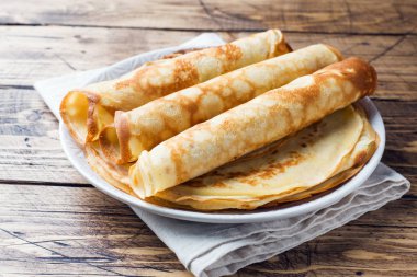 Bir plaka üzerinde ince krep. Ahşap arka plan. Yakın çekim.