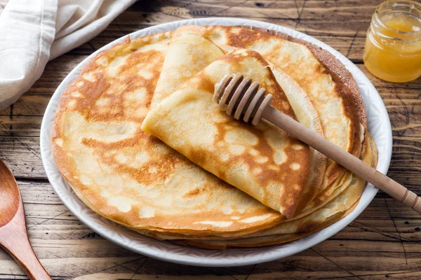 Tunna pannkakor på en tallrik med honung. Trä bakgrund. — Stockfoto