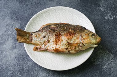 Bir plaka üzerinde pişmiş sazan balık. koyu arka plan. Kopya alanı.