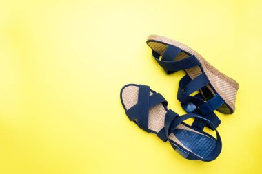 Kopya alanı Sarı zemin üzerine mavi sandalet. kavram yaz tatili. Düz yatıyordu