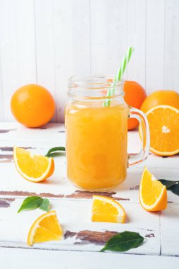 Cam Kavanoz ve Beyaz ahşap rustik zemin üzerine taze portakal portakal suyu.