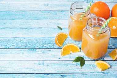 Cam Kavanoz ve mavi bir arka plan üzerinde taze portakal portakal suyu.