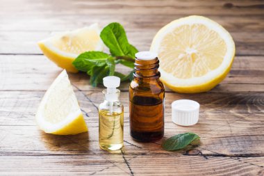 Şişe, taze meyve dilimleri ahşap arka plan üzerinde temel limon yağı. Doğal kokuları.