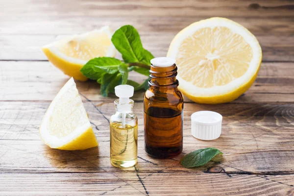 Aceite esencial de limón en botella, rodajas de fruta fresca sobre fondo de madera. Fragancias naturales . — Foto de Stock