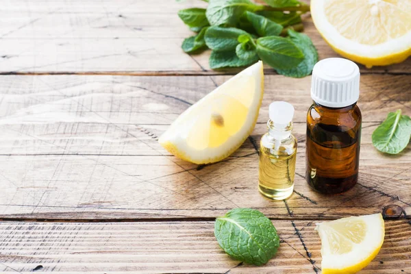 Aceite esencial de limón en botella, rodajas de fruta fresca sobre fondo de madera. Fragancias naturales . — Foto de Stock