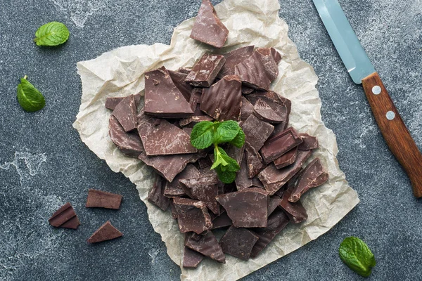 Trozos de chocolate negro triturado con hojas de menta fondo de textura oscura. De cerca. , — Foto de Stock