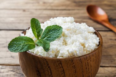 Nane eski ahşap masa üzerinde bir kase ile ev yapımı peynir.