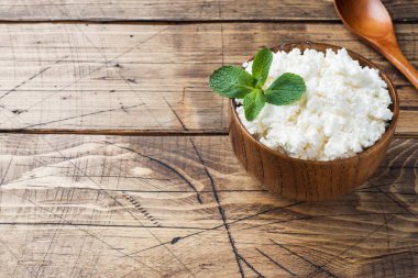 Nane eski ahşap masa üzerinde bir kase ile ev yapımı peynir. Kopya alanı