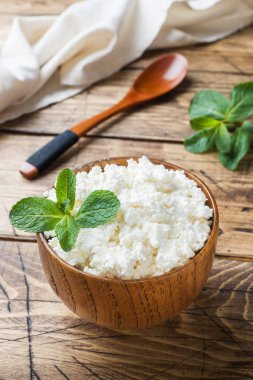 Nane eski ahşap masa üzerinde bir kase ile ev yapımı peynir.