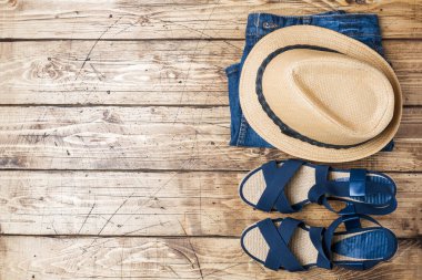 Yaz kadın giyim. Düz yatıyordu moda fotoğraf. Mavi kot pantolon, şapka, mavi sandalet ahşap arka plan üzerinde güneş.