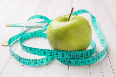 Diyet kavramı. Yeşil elma ve beyaz bir tablo kasette ölçme.