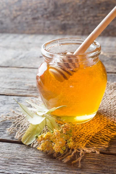 Pot en verre de miel, fleurs de tilleul sur fond en bois — Photo