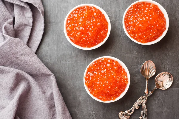 Red salmon caviar in a plate on a dark table. — Stock Photo, Image