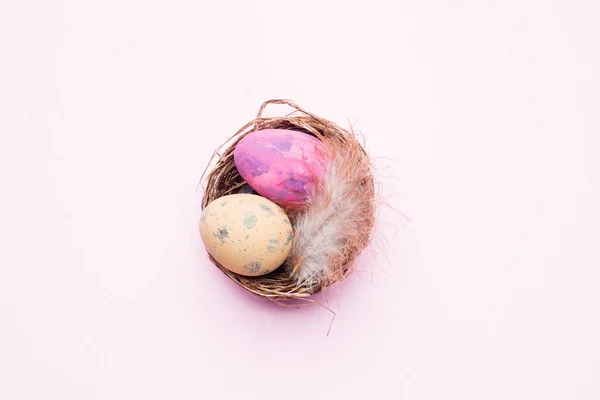 Uovo di Pasqua colorato nel nido su sfondo rosa con spazio per la copia. Sfondo pasquale. Minimalismo — Foto Stock