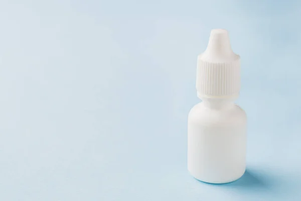 Vit flaska på blå botten. Rund vit plast flaska för medicinsk eller kosmetisk vätska, ögon droppar, olja. Sidovy. — Stockfoto