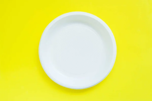 Placas de plástico desechables sobre fondo amarillo brillante con espacio de copia . — Foto de Stock