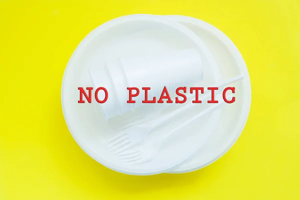 Disposable plastic tableware on bright yellow background with copy space. concept of protest and the words No Plastic — Stock Photo, Image