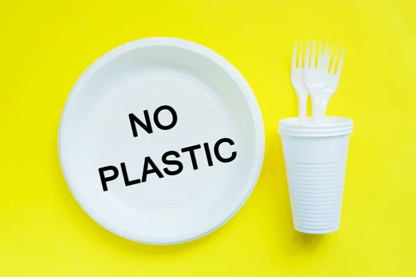 Vajilla de plástico desechable sobre fondo amarillo brillante con espacio de copia. concepto de protesta y las palabras No Plastic — Foto de Stock