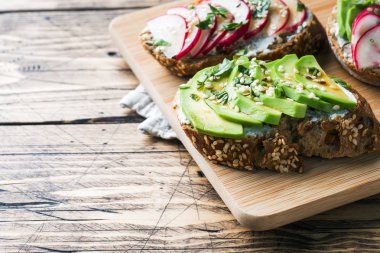 Tahıl ekmeği sandviç süzme peynir, taze avokado ve turp.
