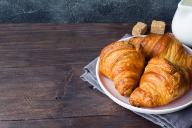 Taze pişmiş kruvasanlar bir plaka, koyu arka plan, kopya alanı.