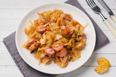 Masaya bir tabak içinde sosis ile haşlanmış lahana. Seçici odak.