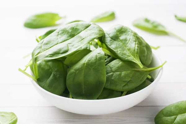 Fresh spinach leaves in a plate on a light table. — Stock Photo, Image