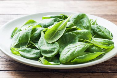 Taze ıspanak kapta rustik ahşap masanın üzerine bırakır..