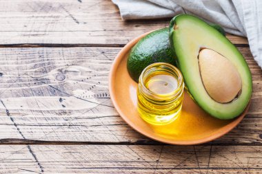 Kopya alanı ile ahşap arka plan üzerinde avokado ve avokado yağı.