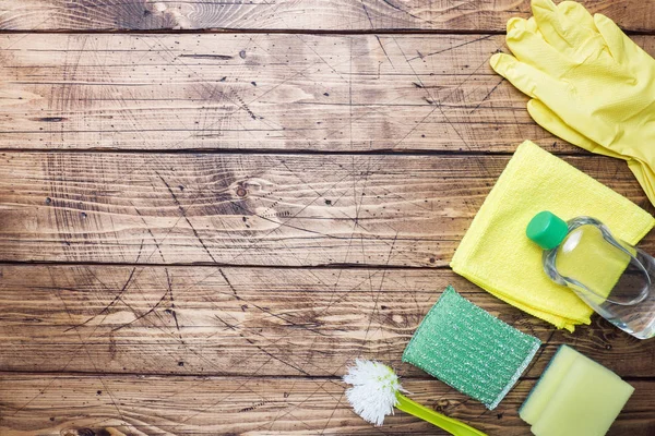 Bottles with detergents, brushes and sponges on wooden background. Colorful cleaning products. Home cleaning concept. Top view, copy space. — Stock Photo, Image