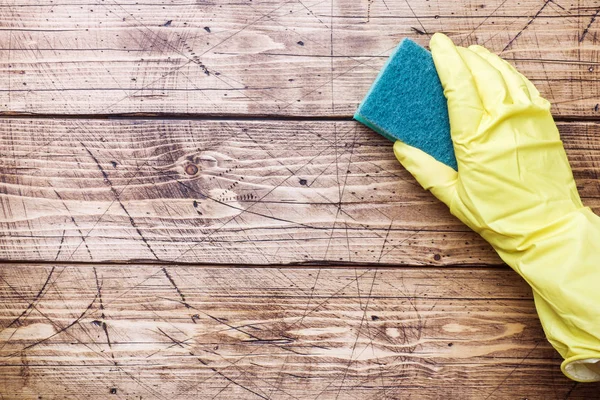 Guante amarillo mano y esponja limpiadora para limpiar sobre fondo de madera. Concepto de limpieza del hogar. Vista superior, espacio de copia —  Fotos de Stock