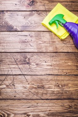 Ahşap arka planda deterjan, fırça ve sünger içeren şişeler. Renkli temizlik ürünleri. Ev temizliği konsepti. Üst görünüm, kopyalama alanı.