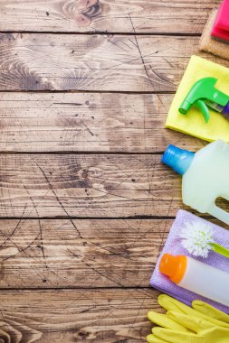 Ahşap arka planda deterjan, fırça ve sünger içeren şişeler. Renkli temizlik ürünleri. Ev temizliği konsepti. Üst görünüm, kopyalama alanı.