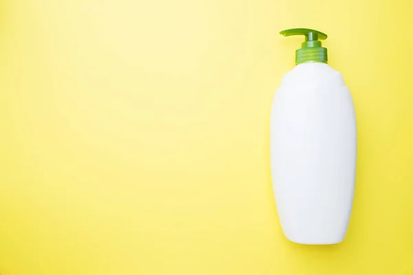 Sarı arka planda beyaz, boş sıvı bir şişe. Ev temizliği konsepti. Üst görünüm, alanı kopyala. — Stok fotoğraf