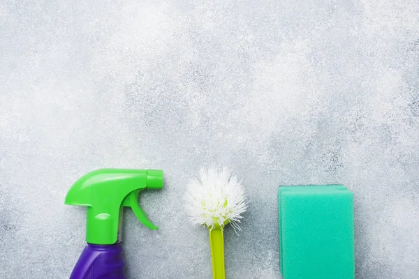 Bottles with detergents, brushes and sponges on concrete background. Colorful cleaning products. Home cleaning concept. Top view, copy space. — Stock Photo, Image