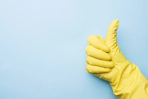 Mano en guantes amarillos para limpiar sobre fondo azul. Pulgares arriba. concepto de limpieza del hogar . —  Fotos de Stock